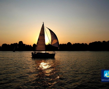 Żagl&oacute;wka na tle zachodu słońca &ndash; Mikołajki wieczorową porą