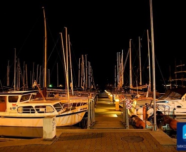 Mikołajki nocą &ndash; port jachtowy pełen świateł i refleks&oacute;w w wodzie